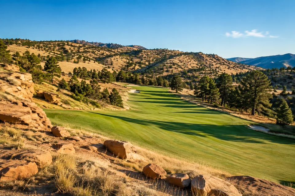 AI-generated illustration of buff sandstone outcrops beside a winding fairway in dry foothills; not an actual course photograph